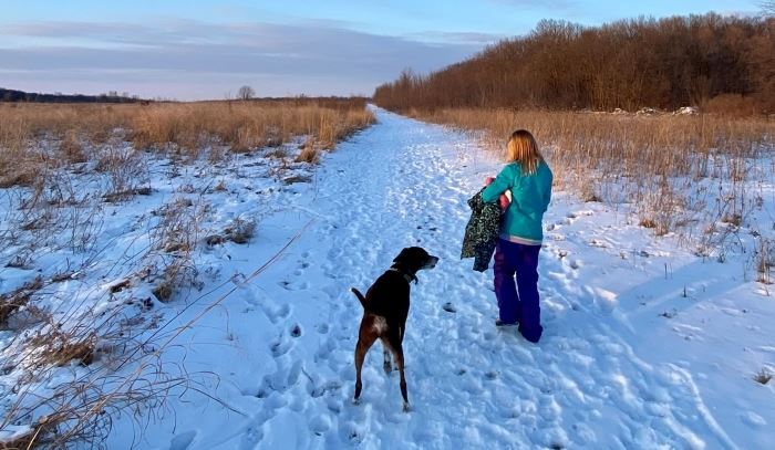 dog and kid walking a snow-covered trail